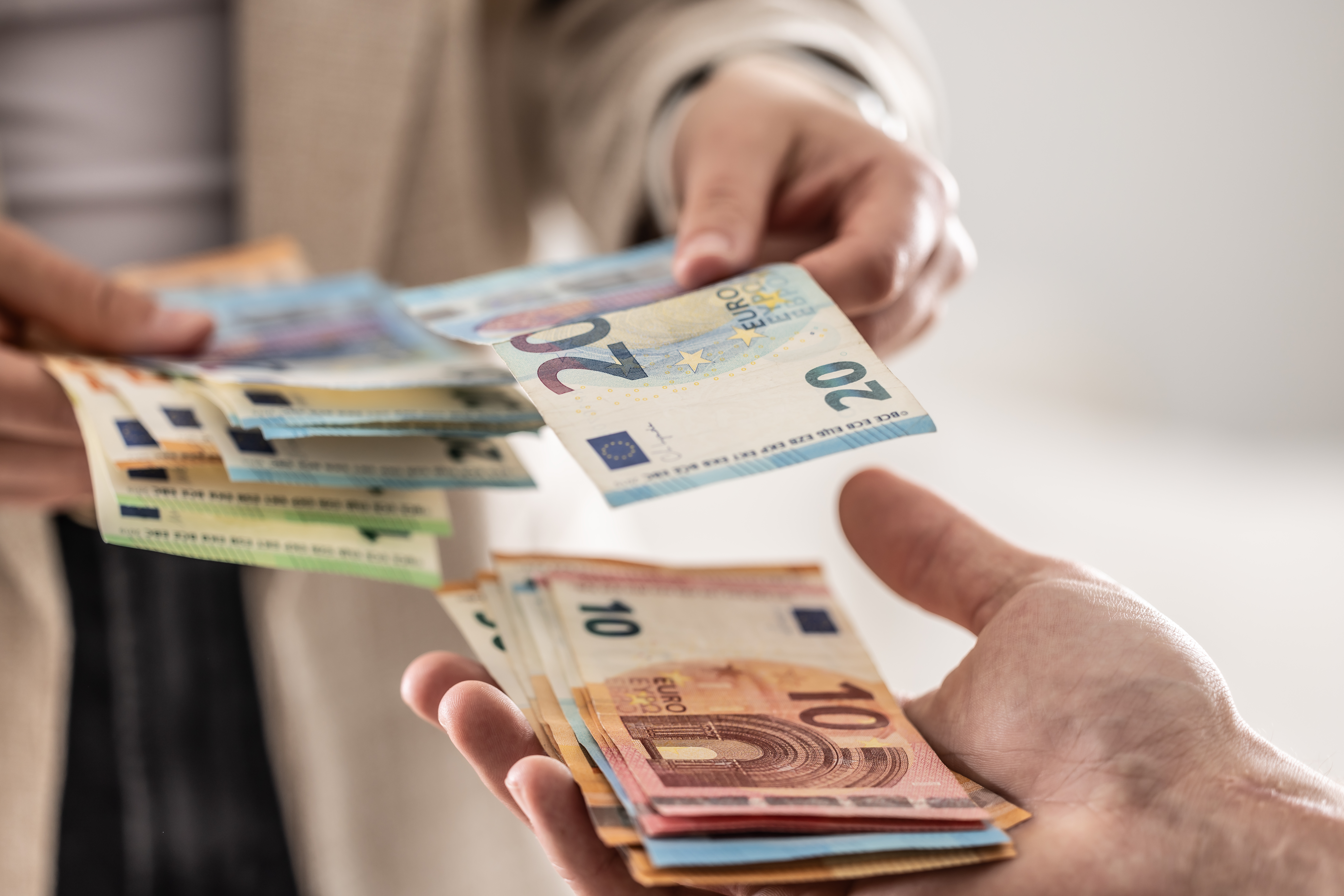 Symbolbild: Eine Hand reicht Geldscheine zu einer anderen Hand.