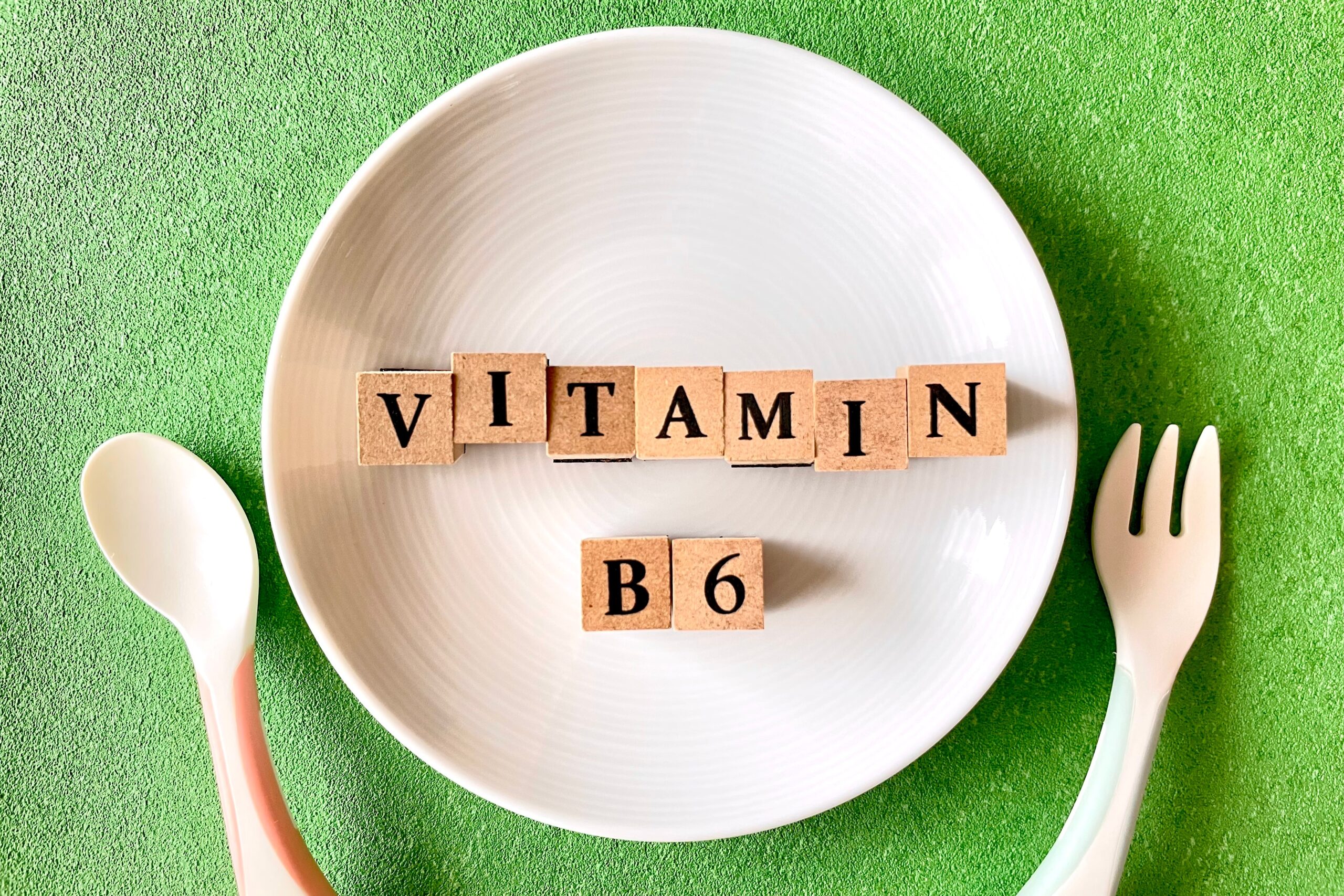 Symbolbild: Ein Teller mit Holzblöcken mit der Aufschrift "Vitamin B6" und daneben liegt Essbesteck.
