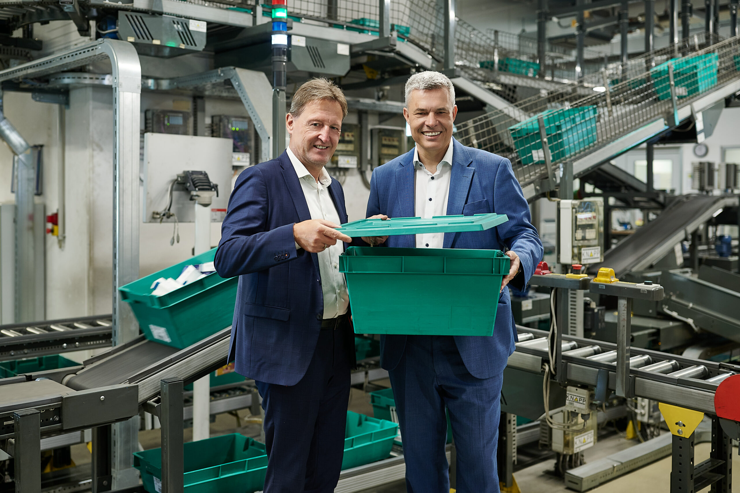 Waberer und Brosch stehen imVertrieb. Sie halten eine grüne Kiste.