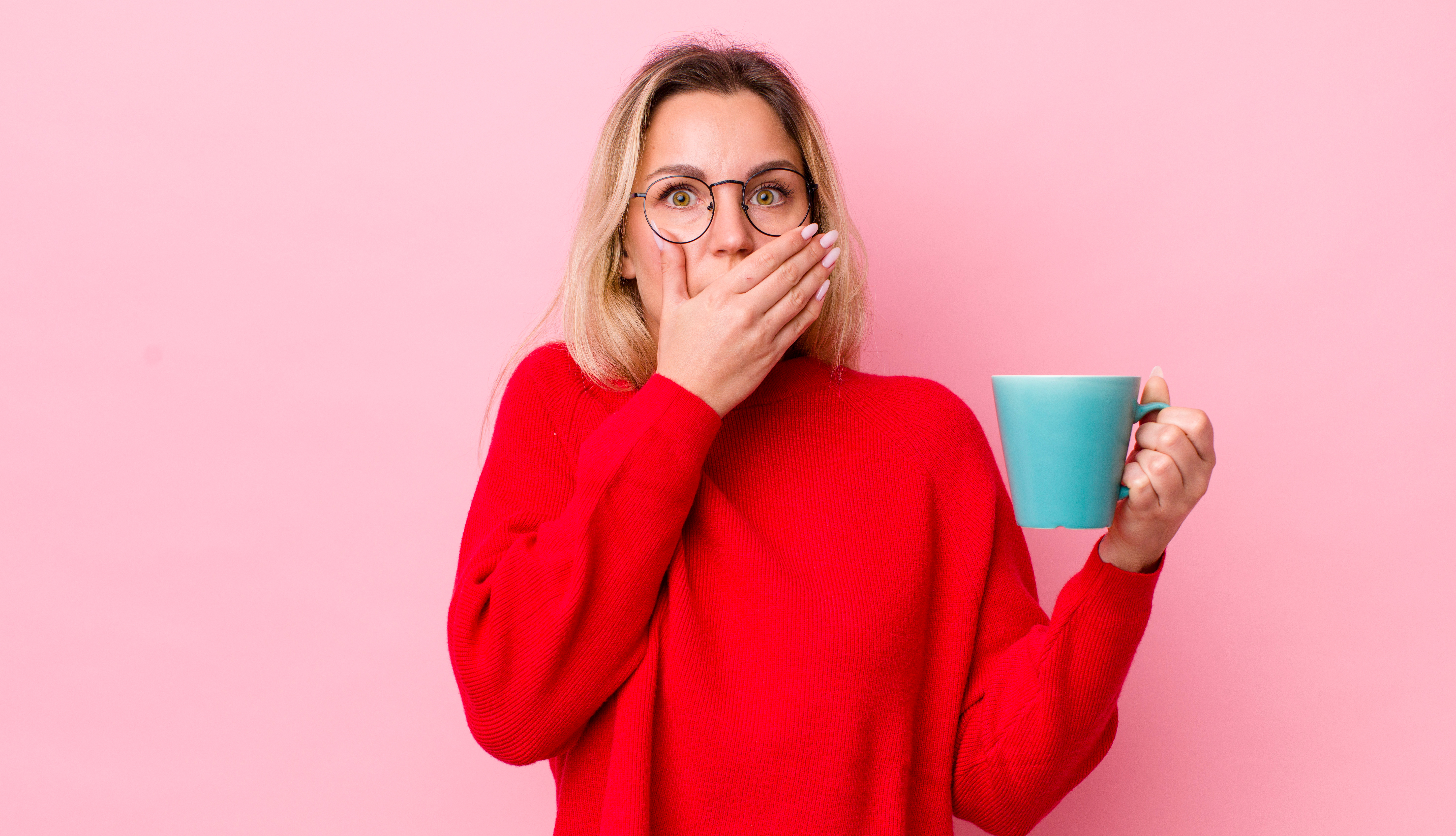 Symbolbild: Eine junge Frau trinkt aus einem Becher und hält sich die Hand vor den Mund.